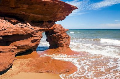 Red Coast Waves break near a sea arch of crumbling red sandstone on the Seaview Coast of Prince Edward Island, Canada. The Atlantic's Gulf of St. Lawrence lies beyond.